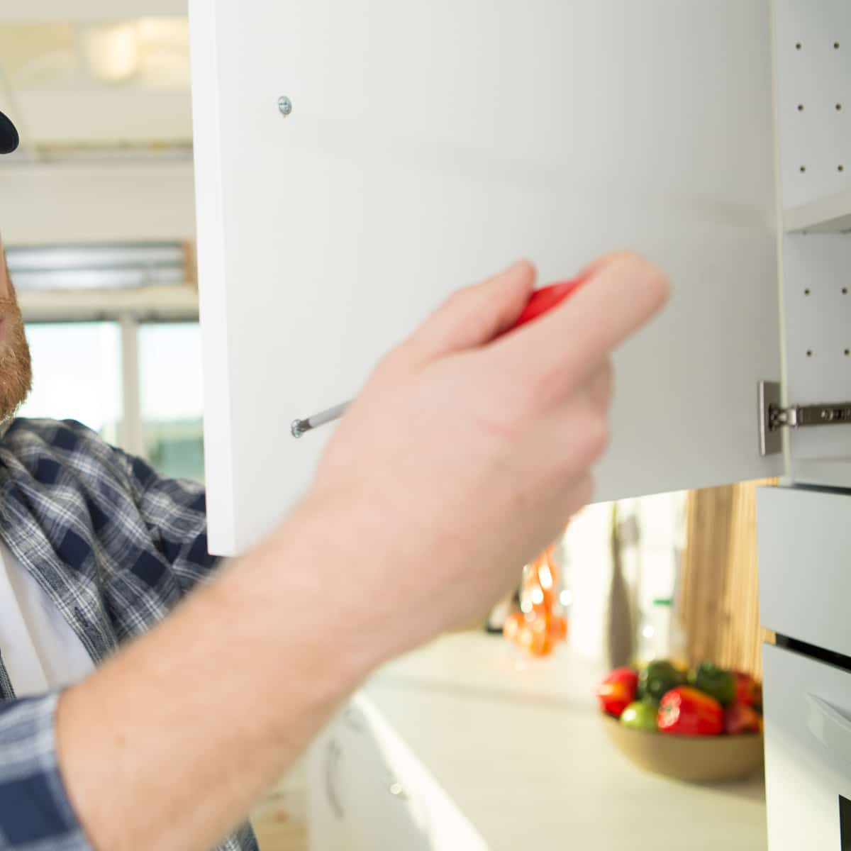 Serrage d'une charnière sur meuble de cuisine lors de l'installation.
